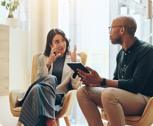 Coworkers sitting in chairs with tablets talking