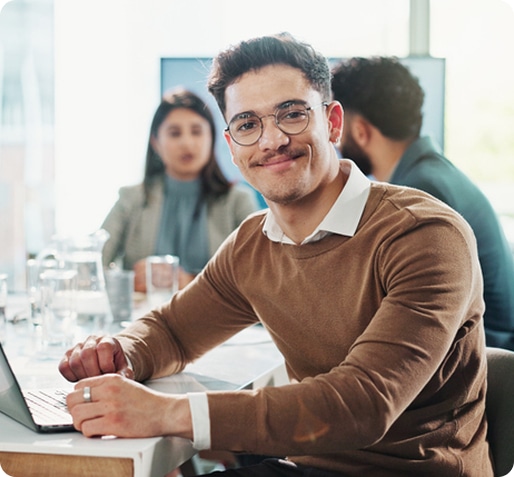Smiling worker at conference table with employees in the background